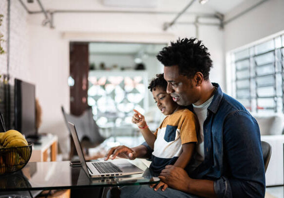 Father using the laptop with son at home Father using the laptop with son at home