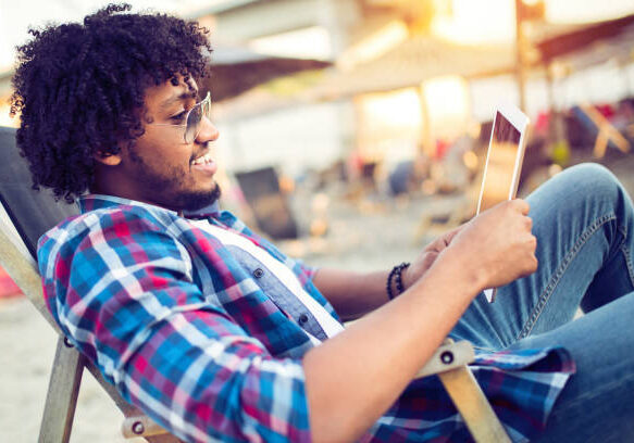 Banking online, portrait of happy african business man with tablet on the beach Banking online, portrait of happy african business man with tablet on the beach