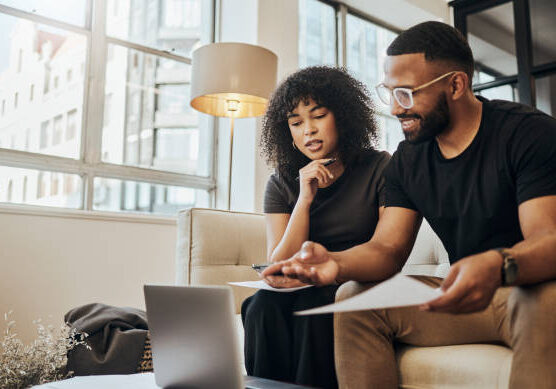 24-55 Finance, account and black couple with laptop on sofa doing online banking. Bills, budget and black man and woman with documents, paperwork and computer doing banking, payment and check bank account